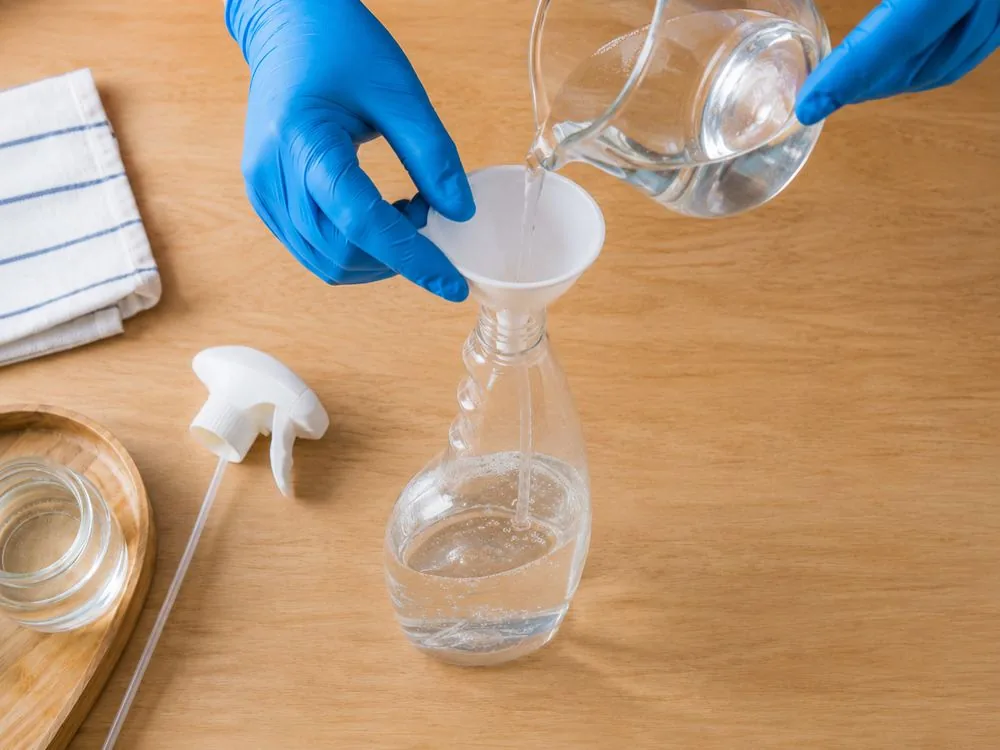 Versement de l'acide citrique dissous dans un flacon spray via un entonnoir
